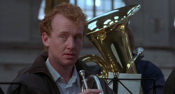 Movie still from “The Full Monty” (1997), directed by Peter Cattaneo – A man holding a trumpet while sitting next to a trombone; Close Up shot, Over the shoulder angle
