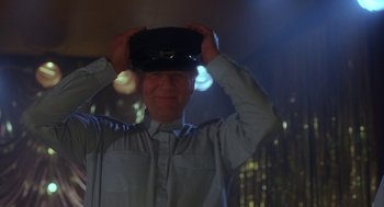 Movie still from “The Full Monty” (1997), directed by Peter Cattaneo – A man holding a hat up to his head; Close Up shot, Low angle