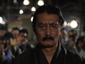 A man with a mustache wearing glasses and a black shirt