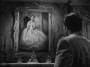 Movie still from “The Furies” (1950), directed by Anthony Mann – A man looking at a painting of a girl in a white dress; Medium shot, Over the shoulder angle