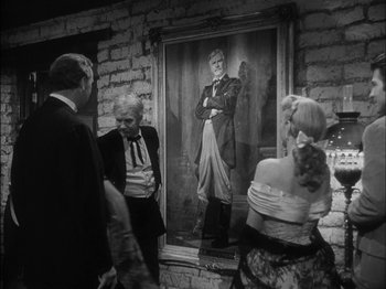 Movie still from “The Furies” (1950), directed by Anthony Mann – Three people are standing in front of a painting of an old man; Medium shot, Over the shoulder angle
