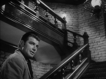 Movie still from “The Furies” (1950), directed by Anthony Mann – A black and white photo of a man standing on the stairs; Medium shot, Low angle