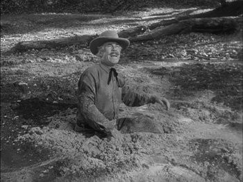 Movie still from “The Furies” (1950), directed by Anthony Mann – An old man sitting in the dirt wearing a cowboy hat; Wide shot, High angle