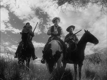 Movie still from “The Furies” (1950), directed by Anthony Mann – A group of men riding horses in a field; Wide shot, Low angle