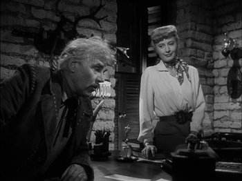 Movie still from “The Furies” (1950), directed by Anthony Mann – An older man and a woman standing next to each other; Medium shot, Low angle