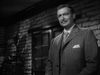 Movie still from “The Furies” (1950), directed by Anthony Mann – A man standing in front of a brick wall; Medium shot, Low angle
