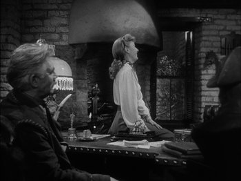 Movie still from “The Furies” (1950), directed by Anthony Mann – A woman standing at a table in front of two other women; Medium shot, Over the shoulder angle