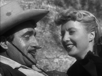 Movie still from “The Furies” (1950), directed by Anthony Mann – A man and a woman smiling for the camera; Close Up shot, Low angle