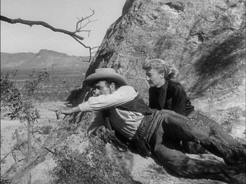 Movie still from “The Furies” (1950), directed by Anthony Mann – A man and a woman sitting on a rock; Wide shot, Low angle