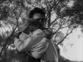 Movie still from “The Furies” (1950), directed by Anthony Mann – A man and a woman hugging in front of a tree; Medium shot, Low angle