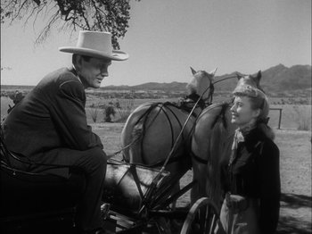 Movie still from “The Furies” (1950), directed by Anthony Mann – An old photo of a man sitting on a horse drawn carriage with a young girl; Medium shot, Over the shoulder angle