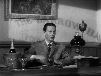 Movie still from “The Furies” (1950), directed by Anthony Mann – A black and white photo of a man sitting at a table; Medium shot, Low angle