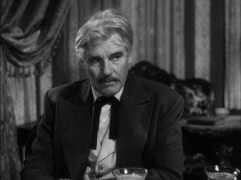 Movie still from “The Furies” (1950), directed by Anthony Mann – An older man wearing a suit and tie sitting at a table; Close Up shot, Over the shoulder angle