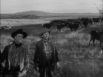 Movie still from “The Furies” (1950), directed by Anthony Mann – Two men standing next to a herd of cattle; Medium shot, Low angle