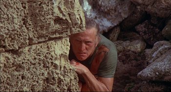 Movie still from “The Fury” (1978), directed by Brian De Palma – A man leaning against a rock wall in a cave; Close Up shot, High angle