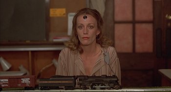 Movie still from “The Fury” (1978), directed by Brian De Palma – A woman sitting in front of a table with a train on top of it; Close Up shot, High angle