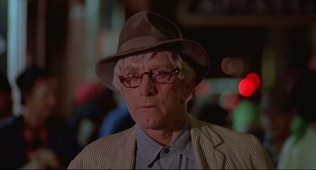 Movie still from “The Fury” (1978), directed by Brian De Palma – An older man wearing glasses and a hat; Close Up shot, Low angle