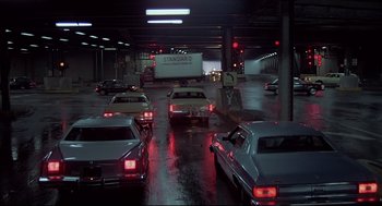 Movie still from “The Fury” (1978), directed by Brian De Palma – A bunch of cars are parked in a parking garage; Extreme Wide shot, High angle