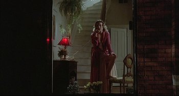 Movie still from “The Fury” (1978), directed by Brian De Palma – A woman talking on the phone while standing in front of a staircase; Wide shot, Low angle