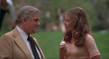 Movie still from “The Fury” (1978), directed by Brian De Palma – A man and a woman are holding a cupcake; Medium shot, Over the shoulder angle