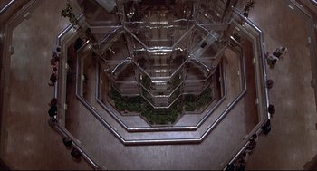 Movie still from “The Fury” (1978), directed by Brian De Palma – Looking down at a very tall building with many stairs; Extreme Wide shot, Overhead angle