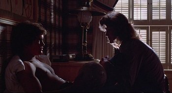 Movie still from “The Fury” (1978), directed by Brian De Palma – Two people sitting on a couch in a living room; Medium shot, Over the shoulder angle