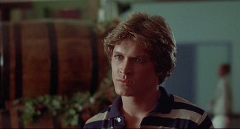 Movie still from “The Fury” (1978), directed by Brian De Palma – A young man with long blonde hair wearing a striped shirt; Close Up shot, Over the shoulder angle