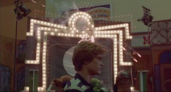Movie still from “The Fury” (1978), directed by Brian De Palma – A young man standing in front of a neon sign; Medium shot, Low angle