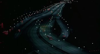Movie still from “The Fury” (1978), directed by Brian De Palma – An aerial view of a highway at night with lights on; Extreme Wide shot, High angle