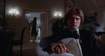 Movie still from “The Fury” (1978), directed by Brian De Palma – A man sitting in a chair in front of a woman; Medium shot, Low angle