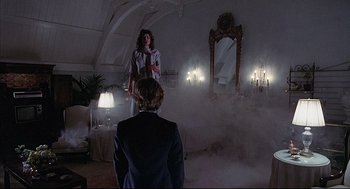 Movie still from “The Fury” (1978), directed by Brian De Palma – A woman standing in front of a man in front of a mirror in a dimly - lit room; Wide shot, Low angle