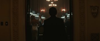 Movie still from “The Gambler” (2014), directed by Rupert Wyatt – A group of people standing in a dark room; Medium shot, Over the shoulder angle