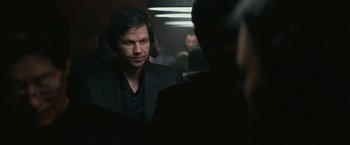 Movie still from “The Gambler” (2014), directed by Rupert Wyatt – A man wearing a suit and tie talking to another man in a suit and tie; Close Up shot, Over the shoulder angle