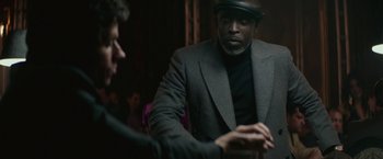 Movie still from “The Gambler” (2014), directed by Rupert Wyatt – A man wearing a hat and a suit talking to another man in a suit; Close Up shot, Over the shoulder angle