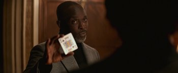 Movie still from “The Gambler” (2014), directed by Rupert Wyatt – A man in a gray suit holding a card in front of a mirror; Close Up shot, Over the shoulder angle