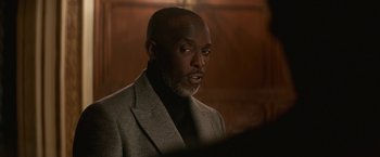 Movie still from “The Gambler” (2014), directed by Rupert Wyatt – A man wearing a suit and tie in a dark room; Close Up shot, Over the shoulder angle