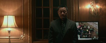 Movie still from “The Gambler” (2014), directed by Rupert Wyatt – A man wearing a suit and tie standing in front of a window; Medium shot, Low angle