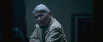 Movie still from “The Gambler” (2014), directed by Rupert Wyatt – An older man sitting in front of a wall; Close Up shot, Over the shoulder angle