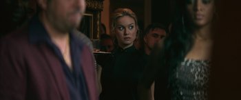 Movie still from “The Gambler” (2014), directed by Rupert Wyatt – A woman in a black dress is standing in front of a group of people; Close Up shot, Over the shoulder angle