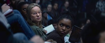 Movie still from “The Gambler” (2014), directed by Rupert Wyatt – Two women sitting in front of each other in front of a group of people; Close Up shot, Over the shoulder angle