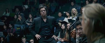 Movie still from “The Gambler” (2014), directed by Rupert Wyatt – A group of people sitting in front of a man holding a cell phone; Medium shot, High angle