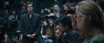 Movie still from “The Gambler” (2014), directed by Rupert Wyatt – A group of people sitting in front of a microphone in a room; Medium shot, High angle