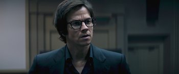 Movie still from “The Gambler” (2014), directed by Rupert Wyatt – A man with glasses and a suit looking at the camera; Close Up shot, Over the shoulder angle