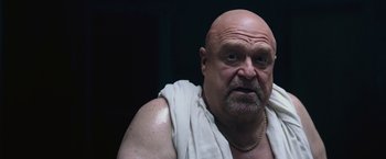 Movie still from “The Gambler” (2014), directed by Rupert Wyatt – A bald man wearing a white towel is looking at the camera; Close Up shot, Low angle