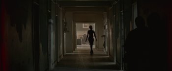 Movie still from “The Gambler” (2014), directed by Rupert Wyatt – A woman walking down a hall way in a dark room; Wide shot, Low angle