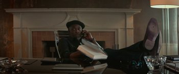 Movie still from “The Gambler” (2014), directed by Rupert Wyatt – A man sitting at a table talking on a phone; Medium shot, Low angle