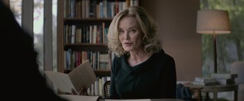 Movie still from “The Gambler” (2014), directed by Rupert Wyatt – An older woman sitting in front of a book shelf; Close Up shot, Over the shoulder angle