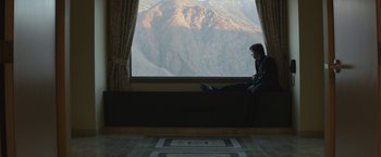 Movie still from “The Gambler” (2014), directed by Rupert Wyatt – A man sitting on a window sill looking out a window; Wide shot, High angle