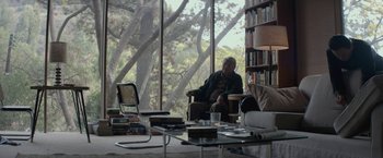 Movie still from “The Gambler” (2014), directed by Rupert Wyatt – A man sitting in a chair in front of a large window; Wide shot, Over the shoulder angle