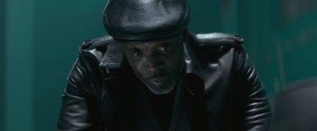 A man wearing a black leather jacket and hat
